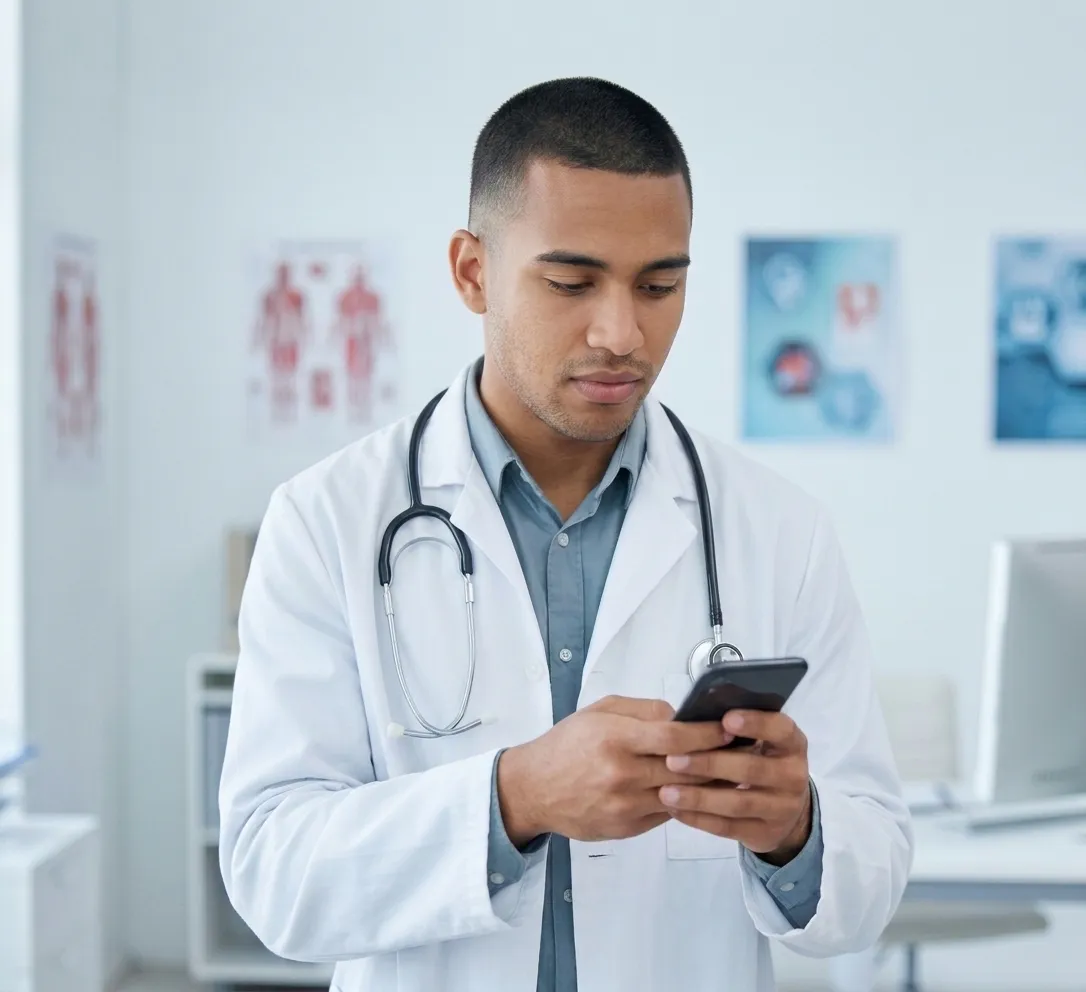Médico con bata blanca revisando en su celular la agenda de pacientes del día