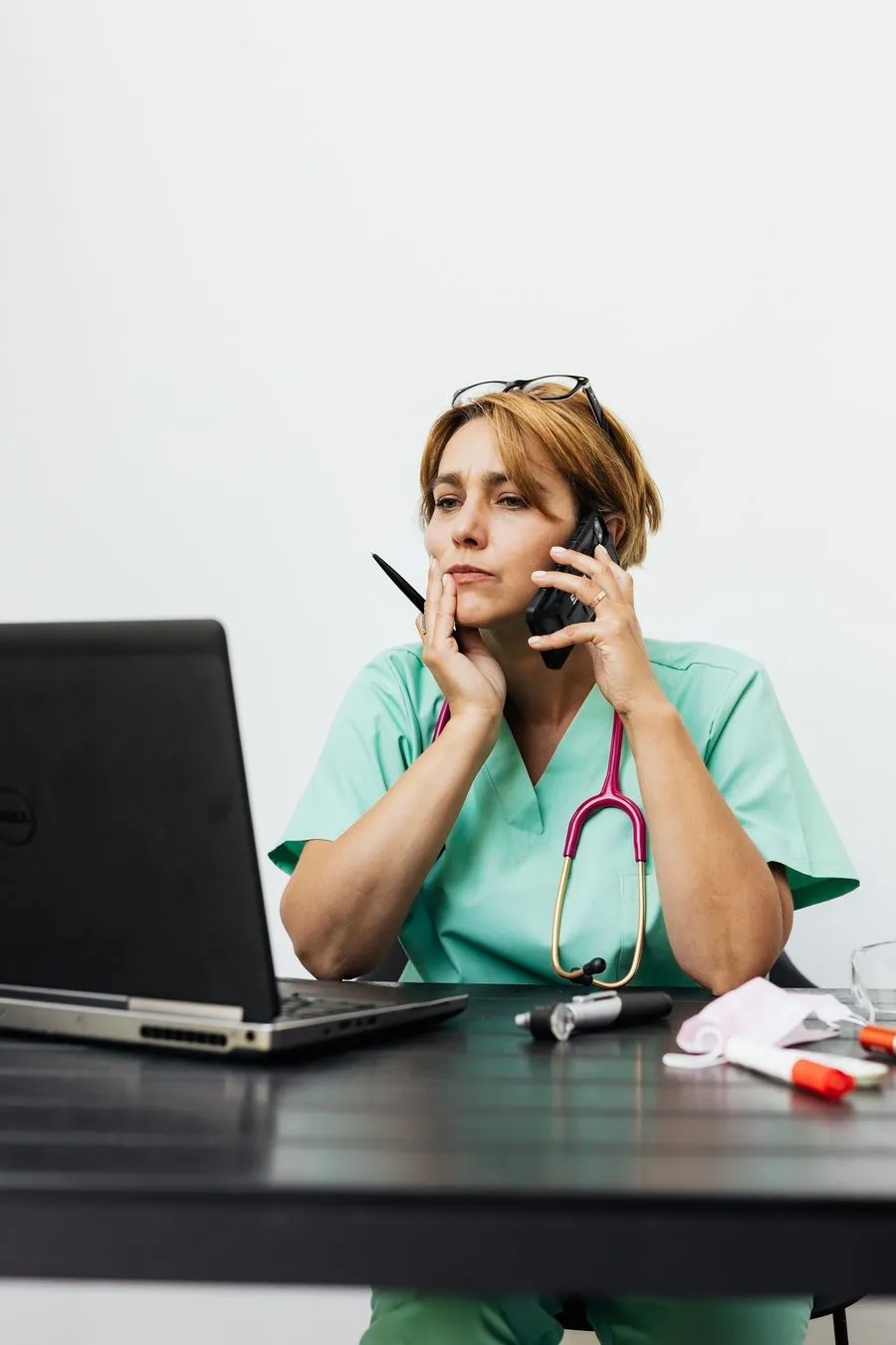 Personal de una clínica atendiendo una llamada, saturado entre el computador y el teléfono